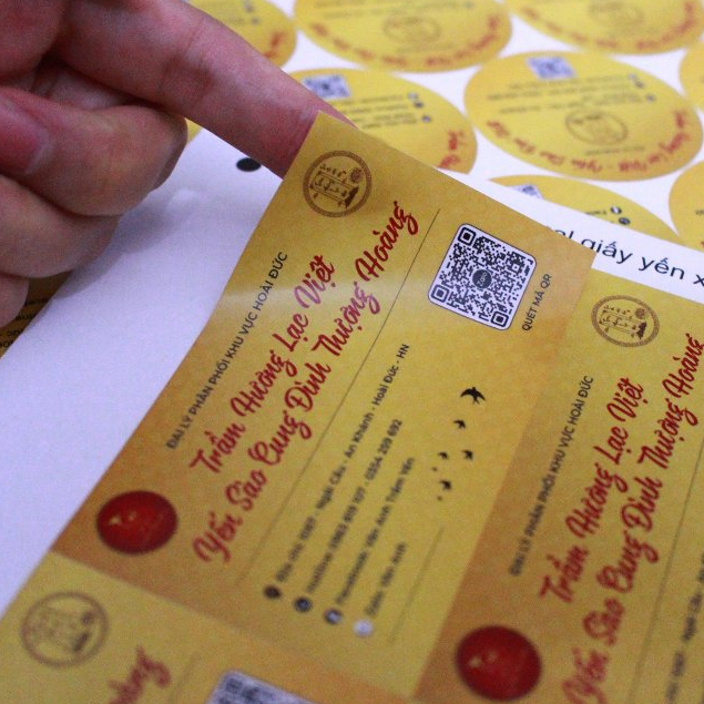 Tem nền vàng có mã QR được cầm trên tay